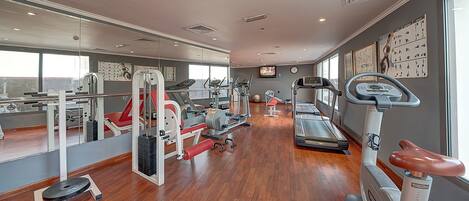 A gym with cardio machines, weightlifting equipment, and mirrors on the walls.