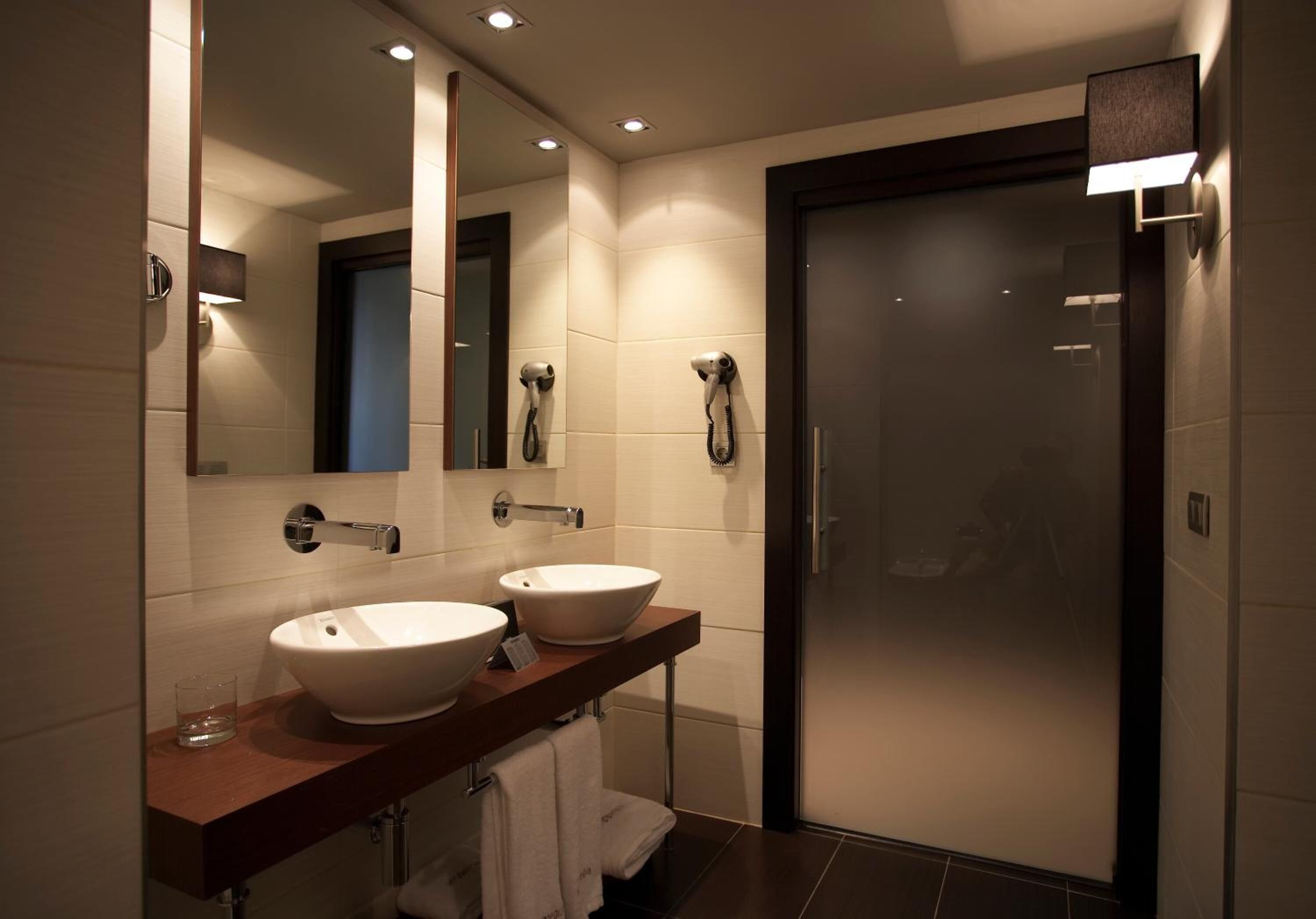 Une salle de bain moderne avec deux lavabos, un miroir et une douche.