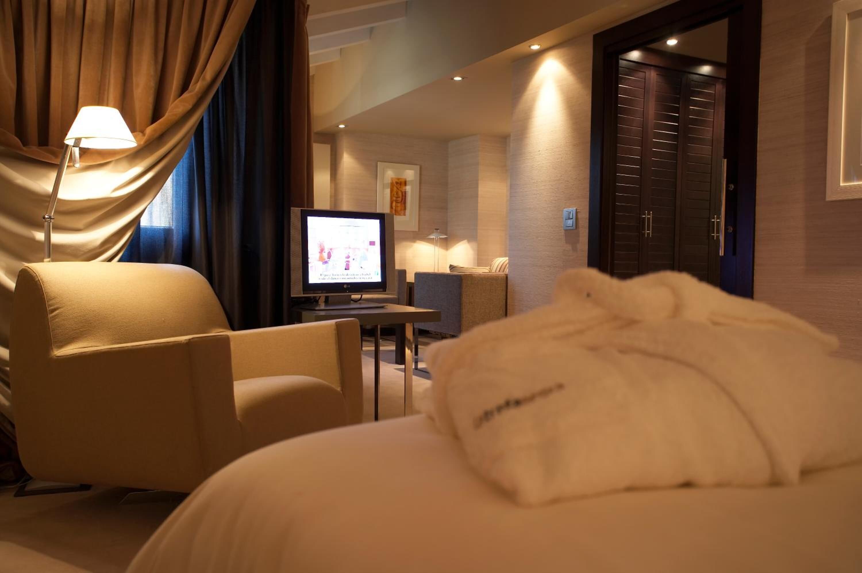 A hotel room with a bed, a desk, a television, and a chair.