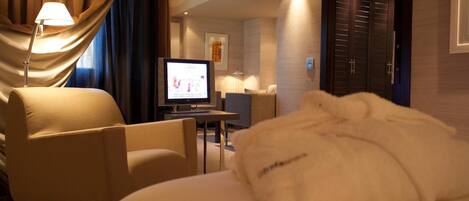 A hotel room with a bed, a desk, a television, and a chair.