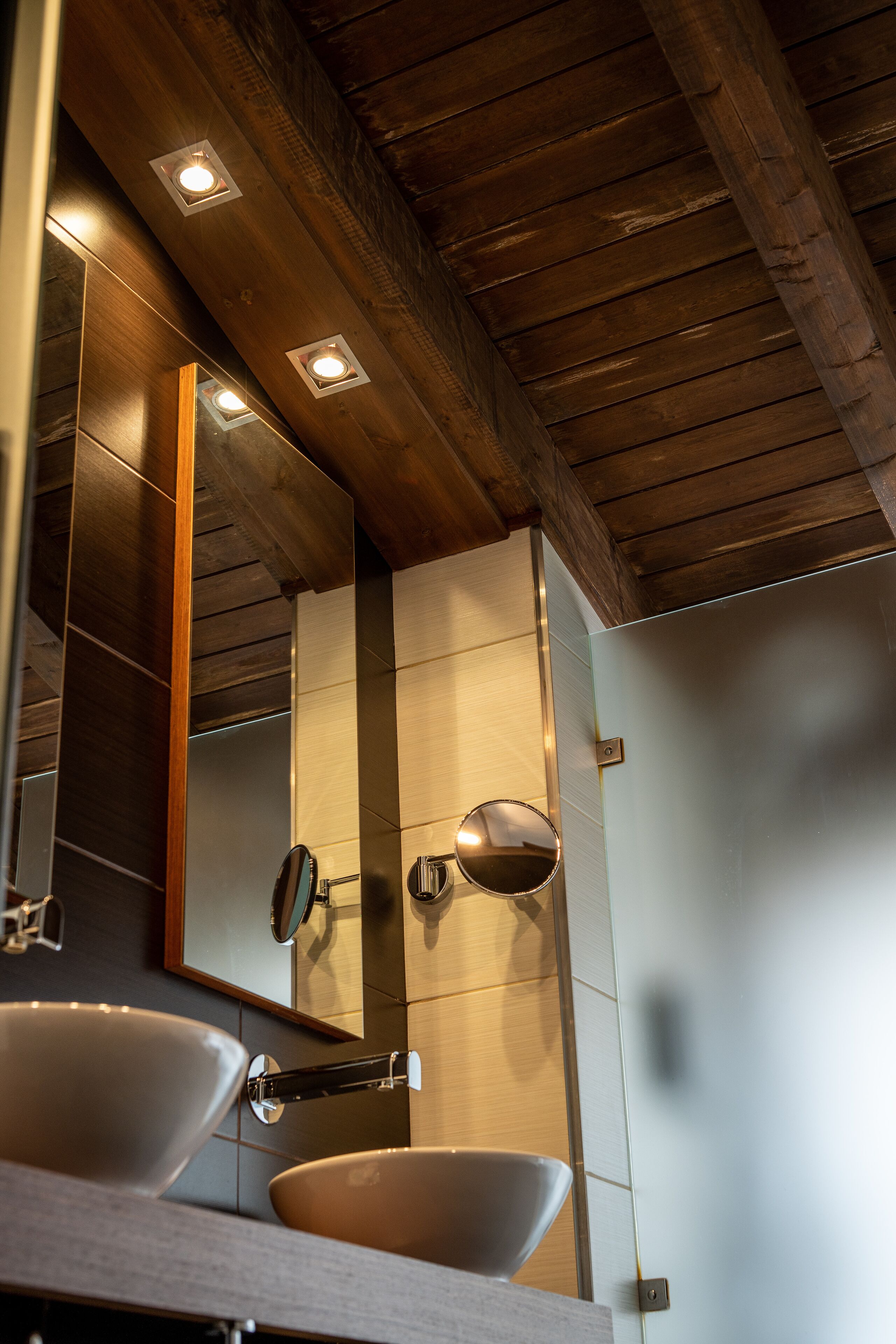 A bathroom with two sinks, a mirror, and recessed ceiling lights.