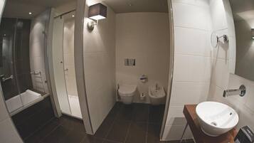 Un baño moderno con ducha de vidrio, bañera, inodoro y lavamanos.