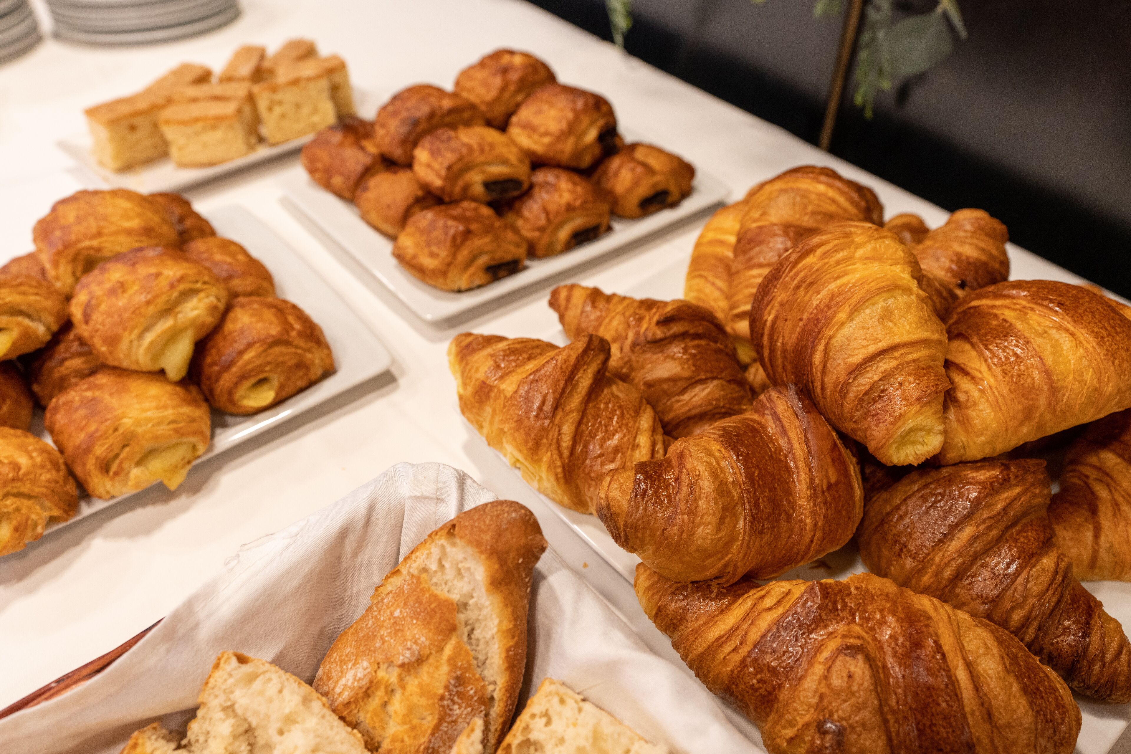 Una mesa con diferentes tipos de pastelería, incluyendo cruasanes y otras preparaciones horneadas.