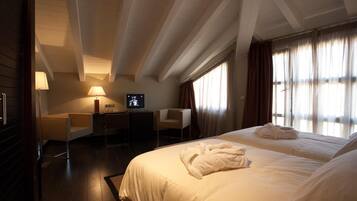 Habitación de hotel con dos camas, un escritorio, una silla, un televisor y una ventana con cortinas.