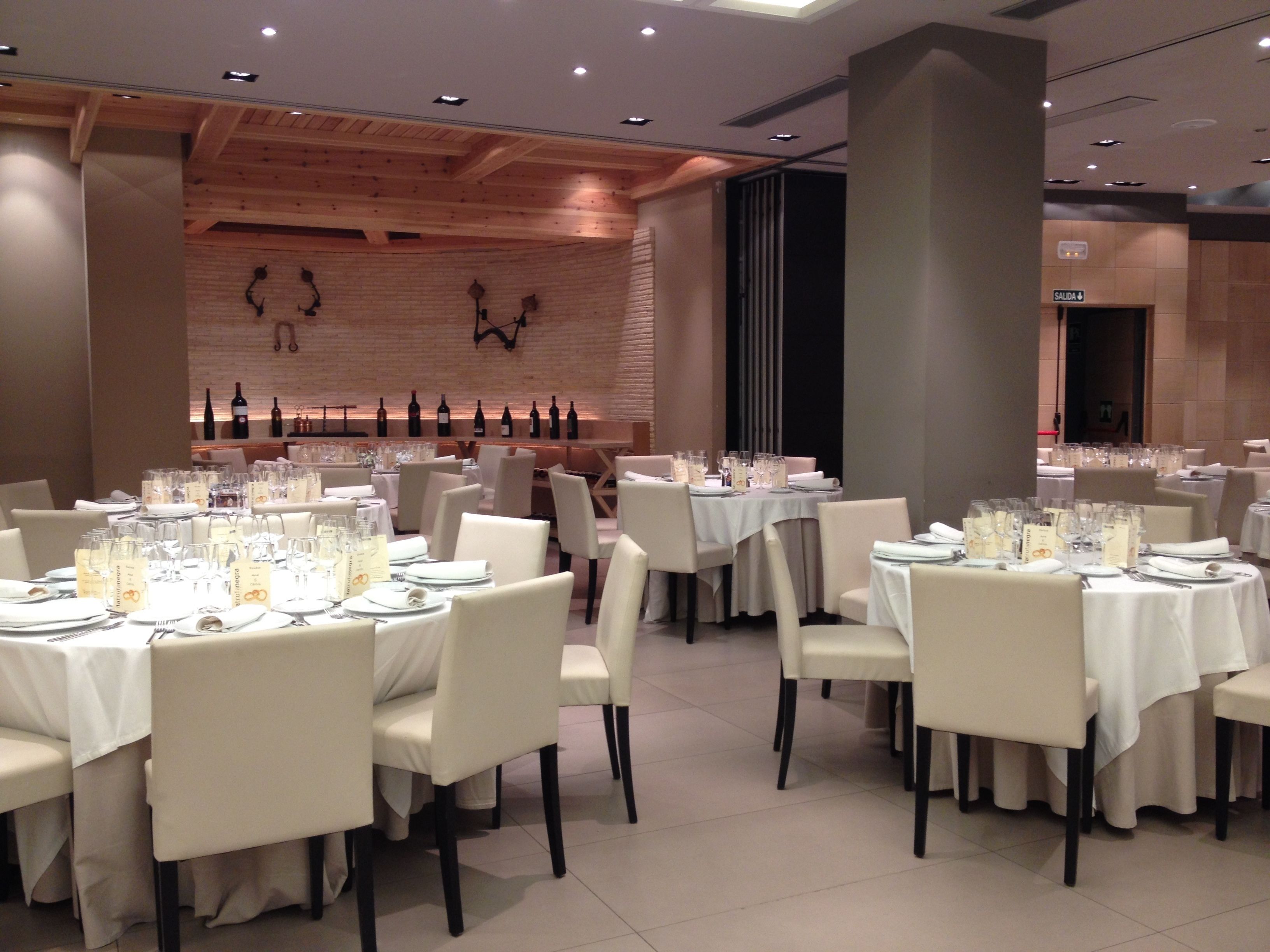 A restaurant with round tables, white tablecloths, and neatly arranged chairs.