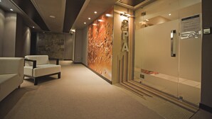 Een wellnessruimte met een receptiebalie, een glazen deur en een wand met een watertextuur ontwerp.