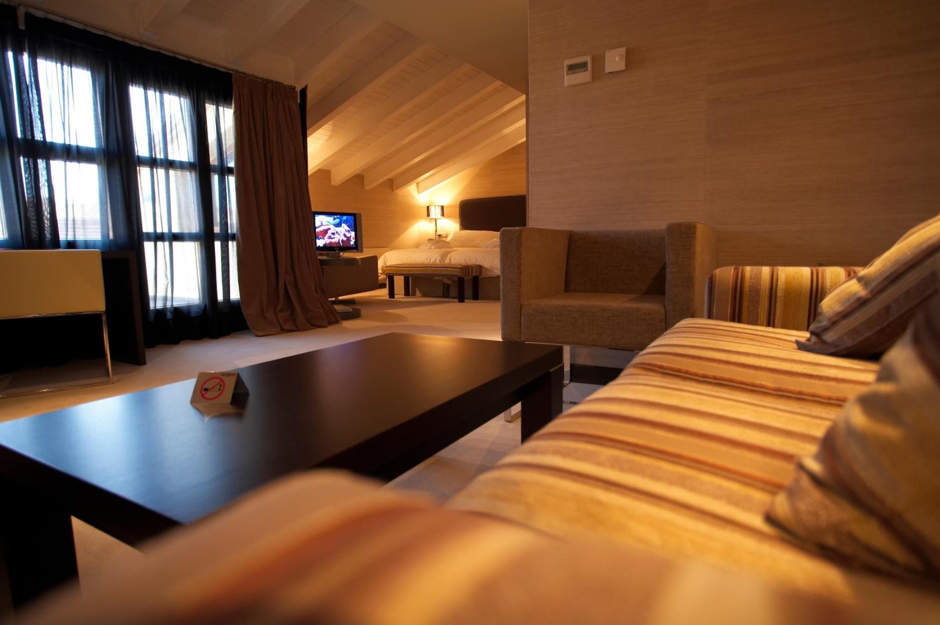 A hotel room with a sofa, a coffee table, a TV, and a bed.
