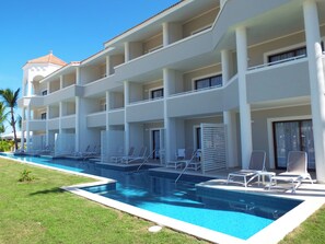 A hotel with a swimming pool, multiple balconies, and a flat roof.