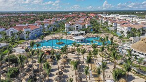 Un complexe hôtelier comprenant plusieurs bâtiments, une piscine centrale et des palmiers.