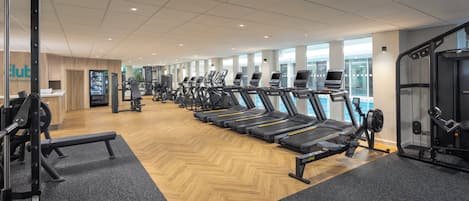 Un gimnasio con cintas de correr, máquinas de pesas y una zona de recepción.