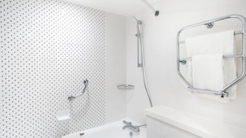 Un baño moderno con un lavabo blanco, grifería cromada, ducha con cabezal de ducha manual y un perchero para toallas.