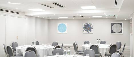 A conference room with round tables, chairs, and water bottles.