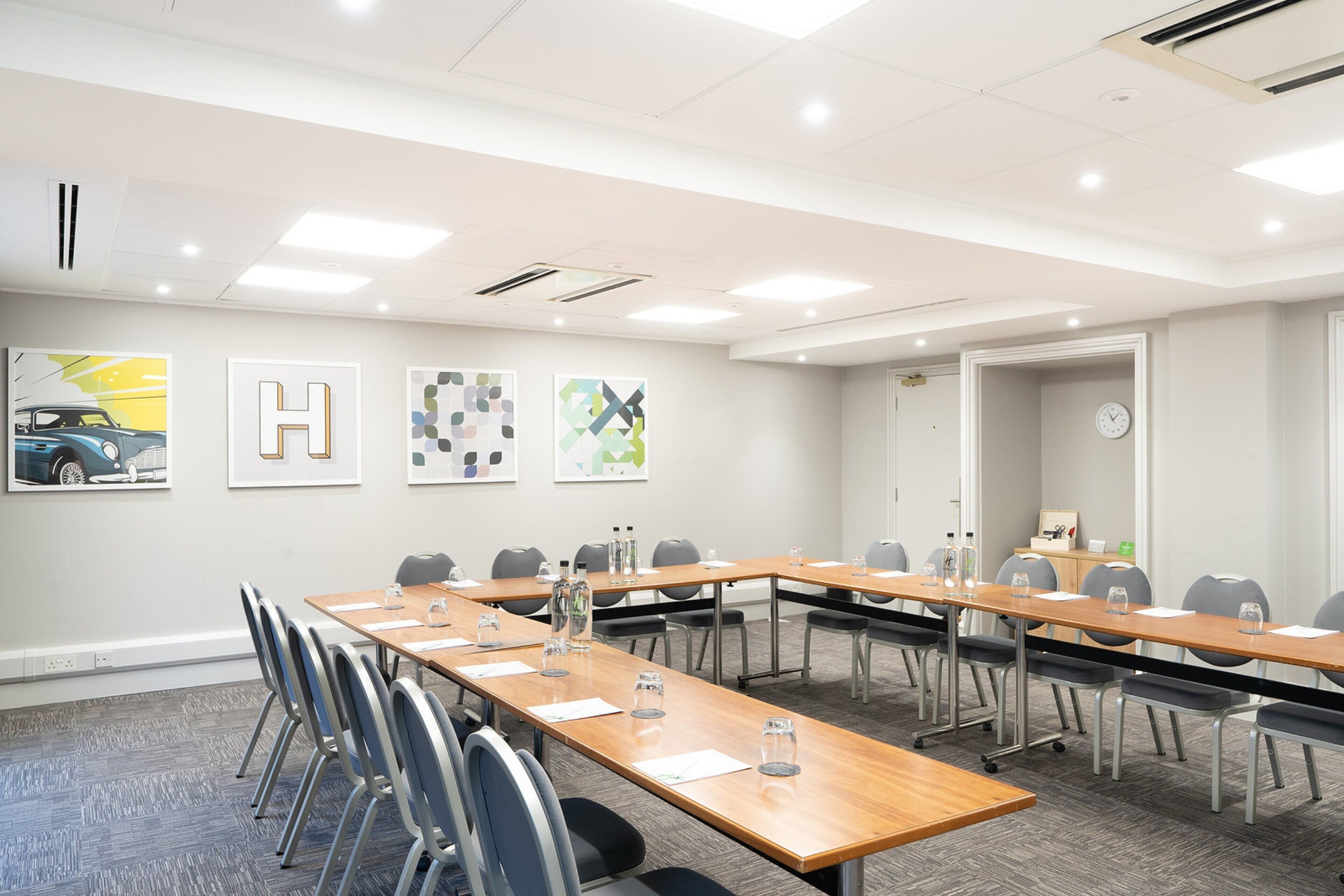 A conference room with a long table, chairs, and artwork on the walls.