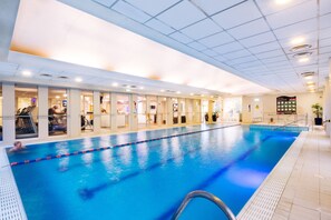 Une piscine intérieure avec des lignes de démarcation bien visibles, un sol carrelé et un plafond doté d’un éclairage encastré.