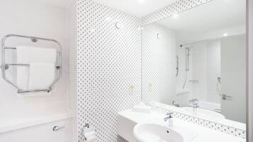Un baño moderno con lavamanos, espejo y toallero blancos.