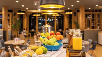 A breakfast buffet with fruits, beverages, and breakfast items.