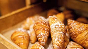 A wooden display case containing various pastries, including croissants dusted with powdered sugar.