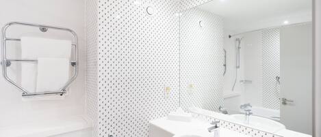 Un baño moderno con un lavamanos, espejo y toallero blancos.