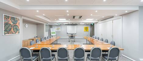 A conference room with a long table, chairs, and a whiteboard.