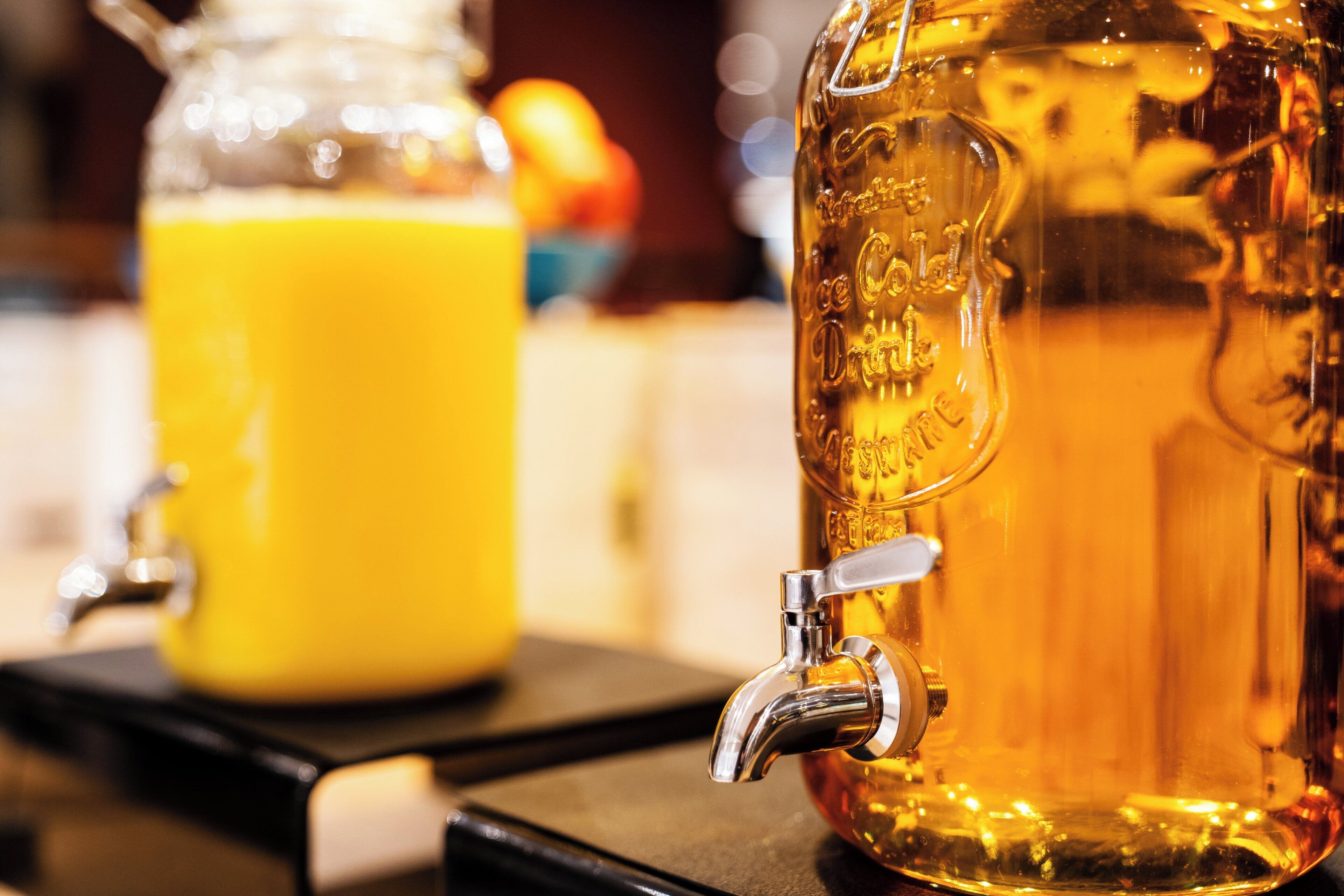 A beverage dispenser with a tap and a glass container in the background.