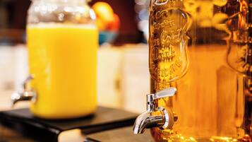 A beverage dispenser with a tap and a glass container in the background.