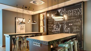 A bar area with a chalkboard menu, bar stools, pendant lighting, and a wooden bar counter.