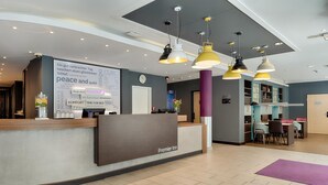 A hotel reception area with a modern design, including a reception desk, pendant lighting, and a wall with text.