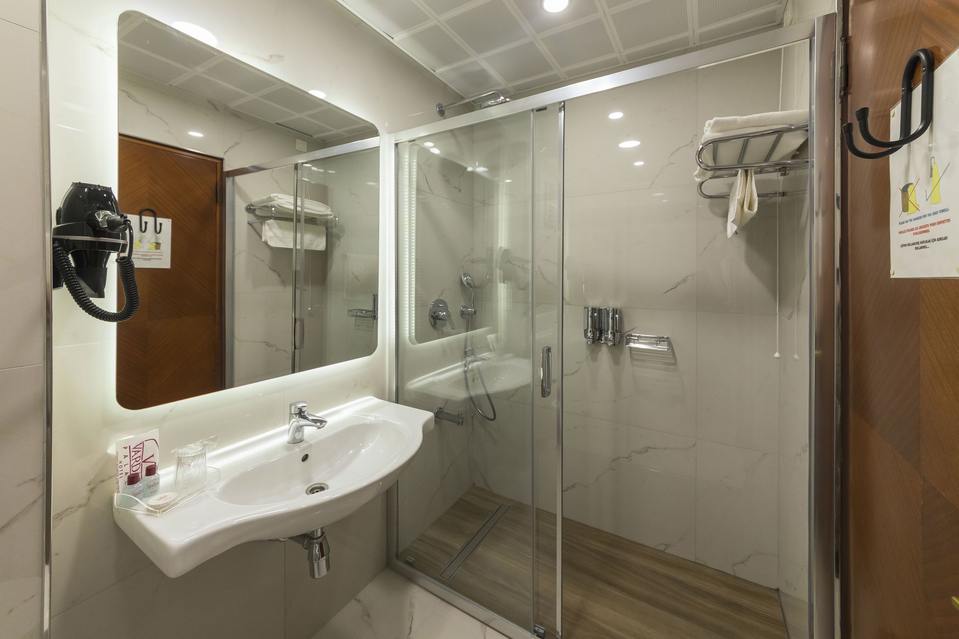 A modern bathroom with a glass-enclosed shower, a white sink, and a mirror above it.