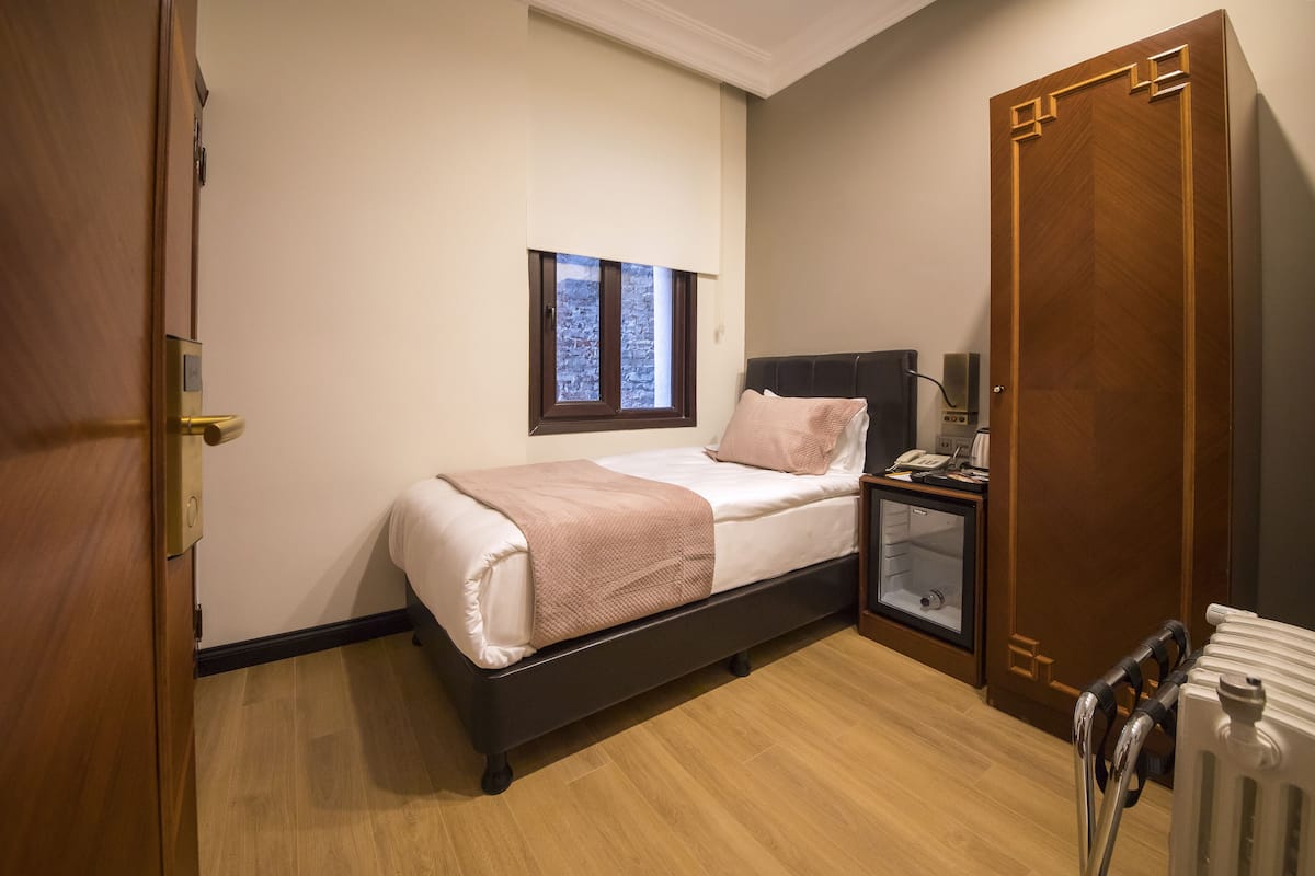 A bedroom with a bed, bedside table, nightstand, and a radiator.