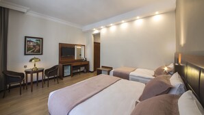 A hotel room with two beds, a desk with a chair, a TV, and a painting on the wall. - Vardar Palace Hotel - Special Class (Istanbul)