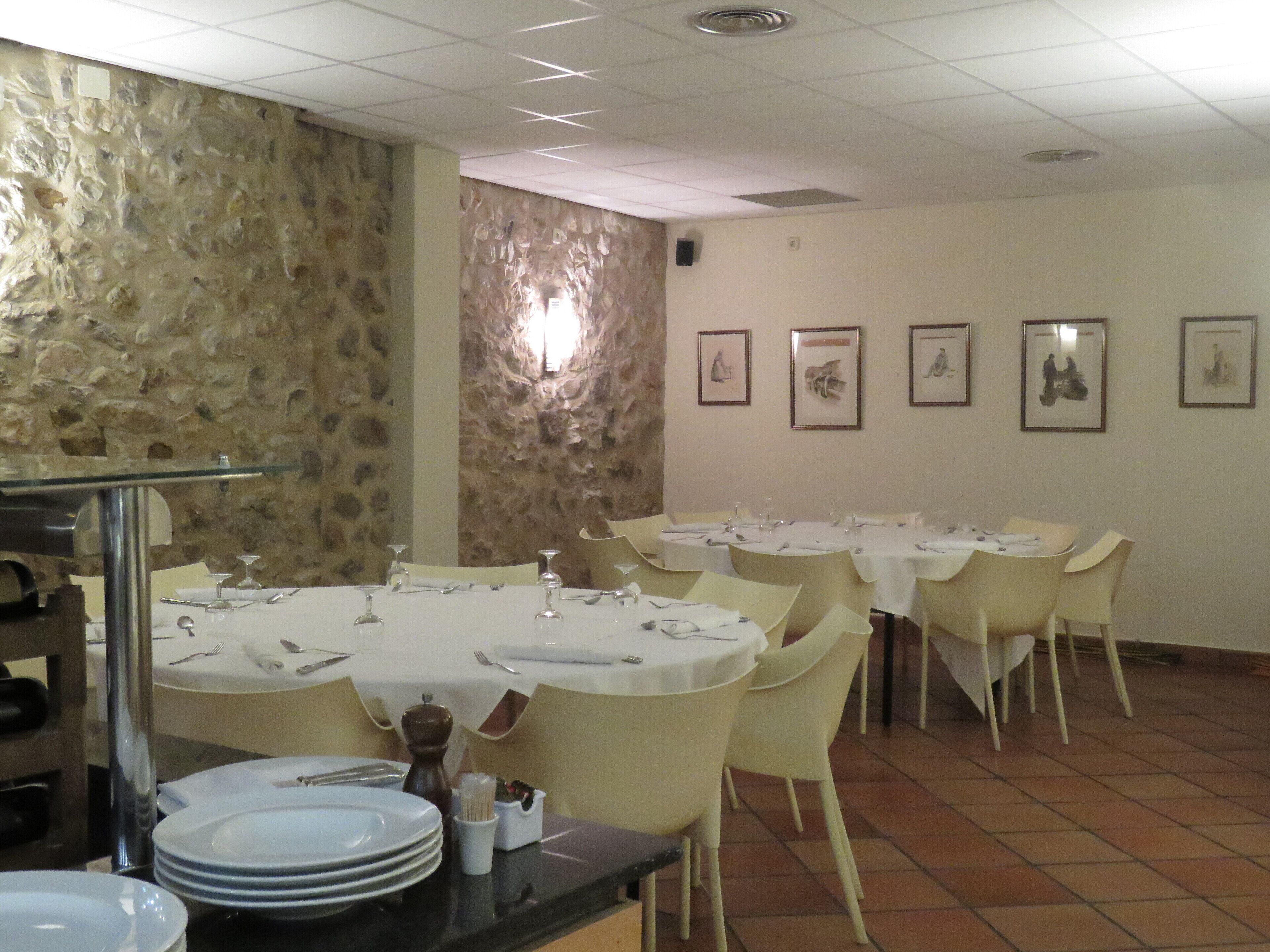 A dining area with round tables, chairs, and a stone wall.