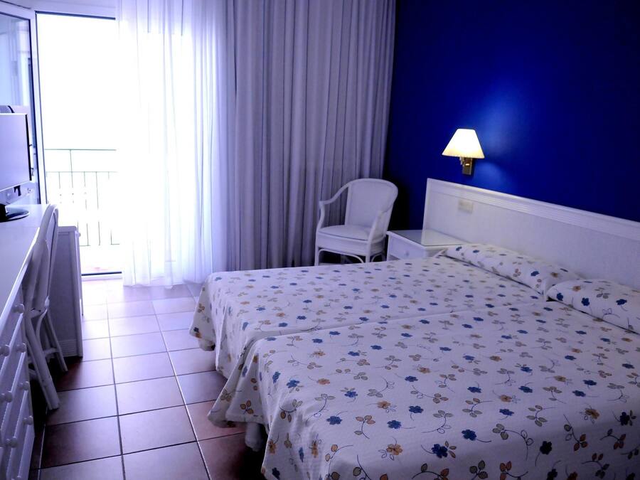 Ein Hotelzimmer mit Bett, Stuhl, Schreibtisch und Lampe.