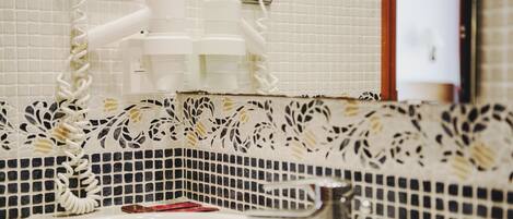 A bathroom with a white sink, a mirror, and a towel rack. There are two electrical outlets on the wall.
