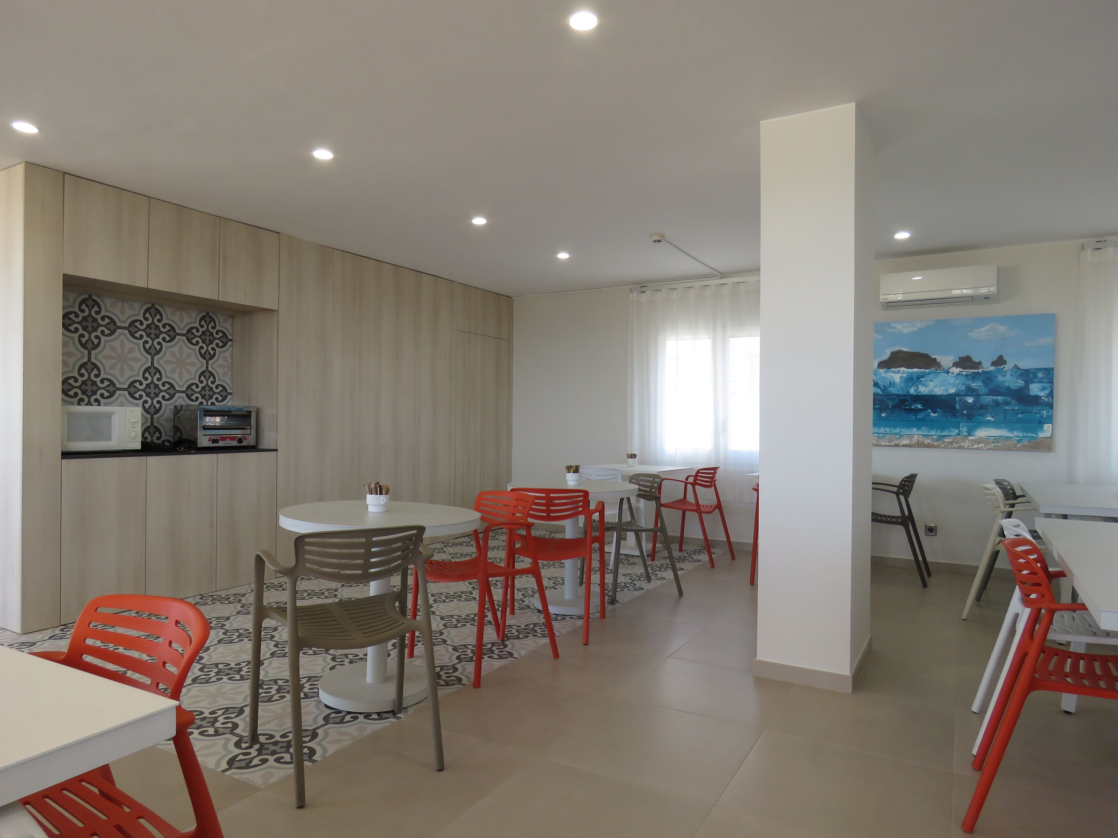 Un comedor moderno con una mesa larga y varias sillas, un microondas y un tostador en la pared.
