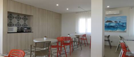 Un comedor moderno con una mesa larga y varias sillas, un microondas y un tostador en la pared.