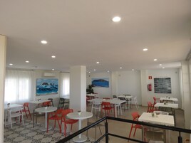 A dining area with tables and chairs, paintings on the walls, and a sign with text.