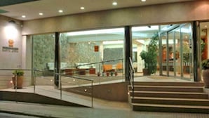 Ein Hotel mit Glasfassade, einer Treppe zum Eingang und einer Zimmerpflanze links.
