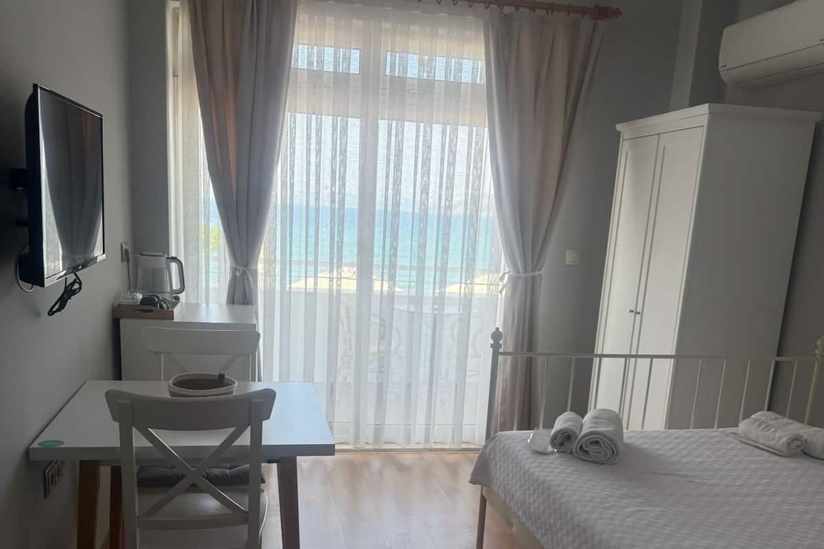 Een hotelkamer met een bed, bureau, stoel, televisie en garderobe.