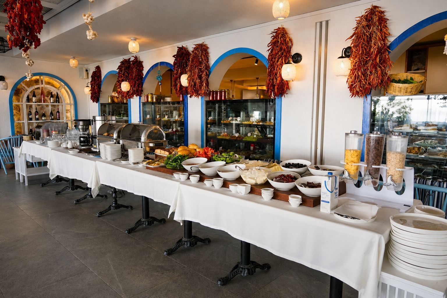 A buffet setup with various food items and beverages, a coffee station, and decorative elements like hanging dried leaves.