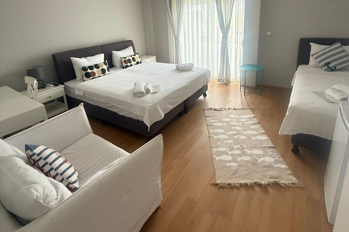 Een moderne hotelkamer met een groot bed, een kleiner bed, een bank en een bureau.