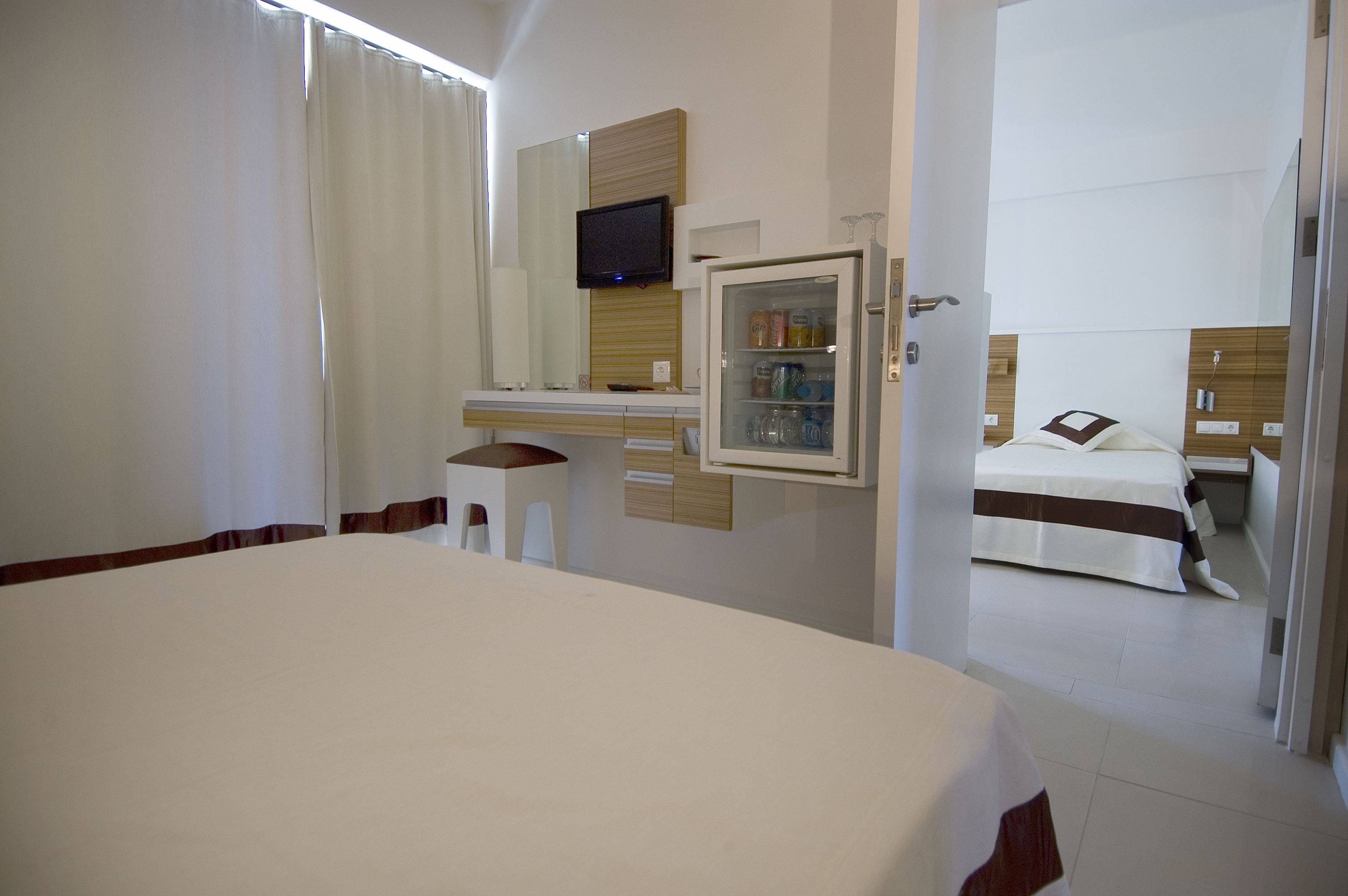 A hotel room with a bed, a desk, a television, and a minibar.