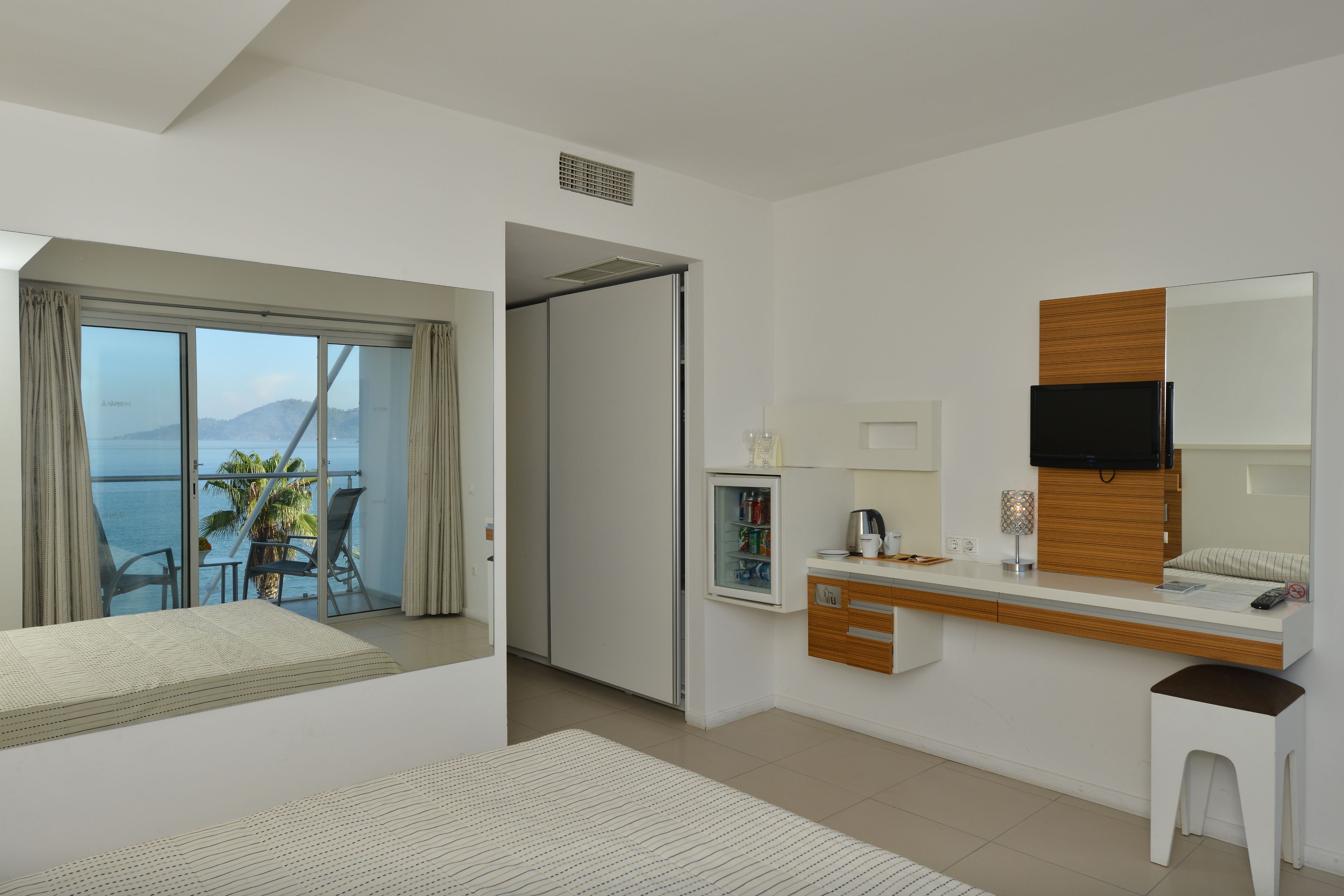 Una camera d'albergo moderna con balcone, angolo cottura, televisione a schermo piatto e un letto.