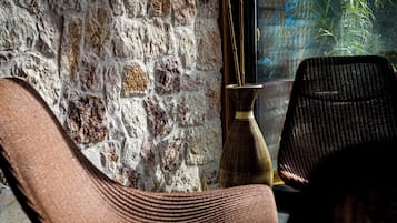 A room with a rustic brick wall, a wooden floor, and a window with a view of greenery.