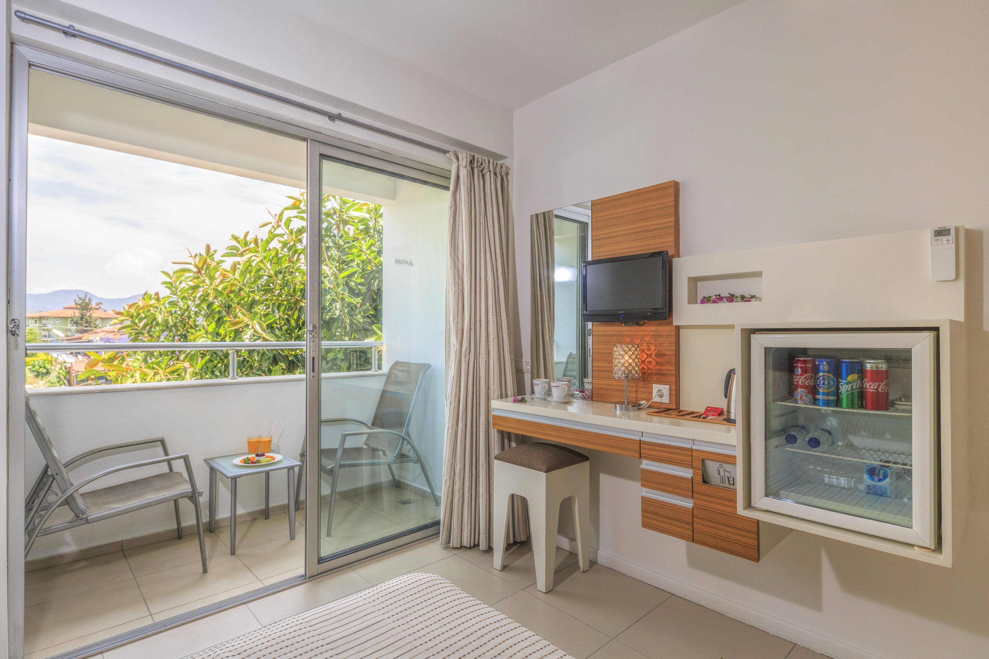 Una habitación de hotel moderna con balcón, escritorio, televisión y minibar.