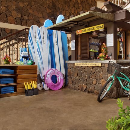 A surf shop with surfboards, a bicycle, and a sign for beach rentals.