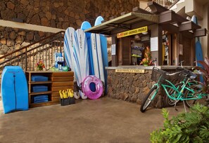 A surf shop with surfboards, a bicycle, and a sign for beach rentals.