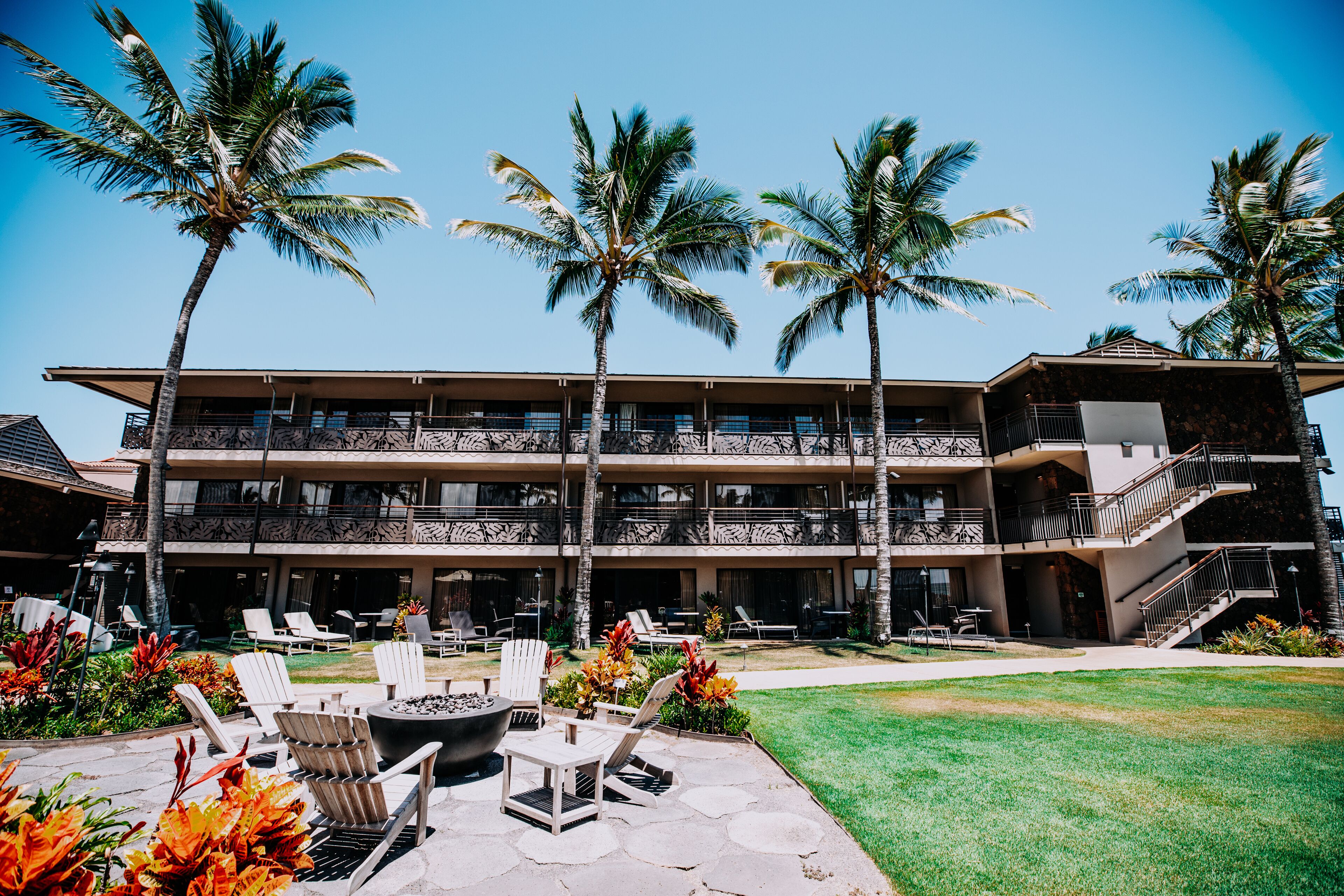 A multi-story hotel with outdoor seating and palm trees.