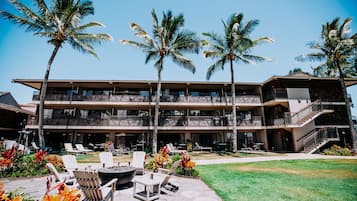 A multi-story hotel with outdoor seating and palm trees.