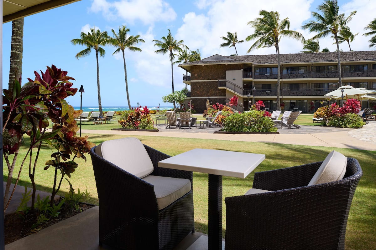 A hotel patio with wicker furniture, a pool, and a view of the ocean.