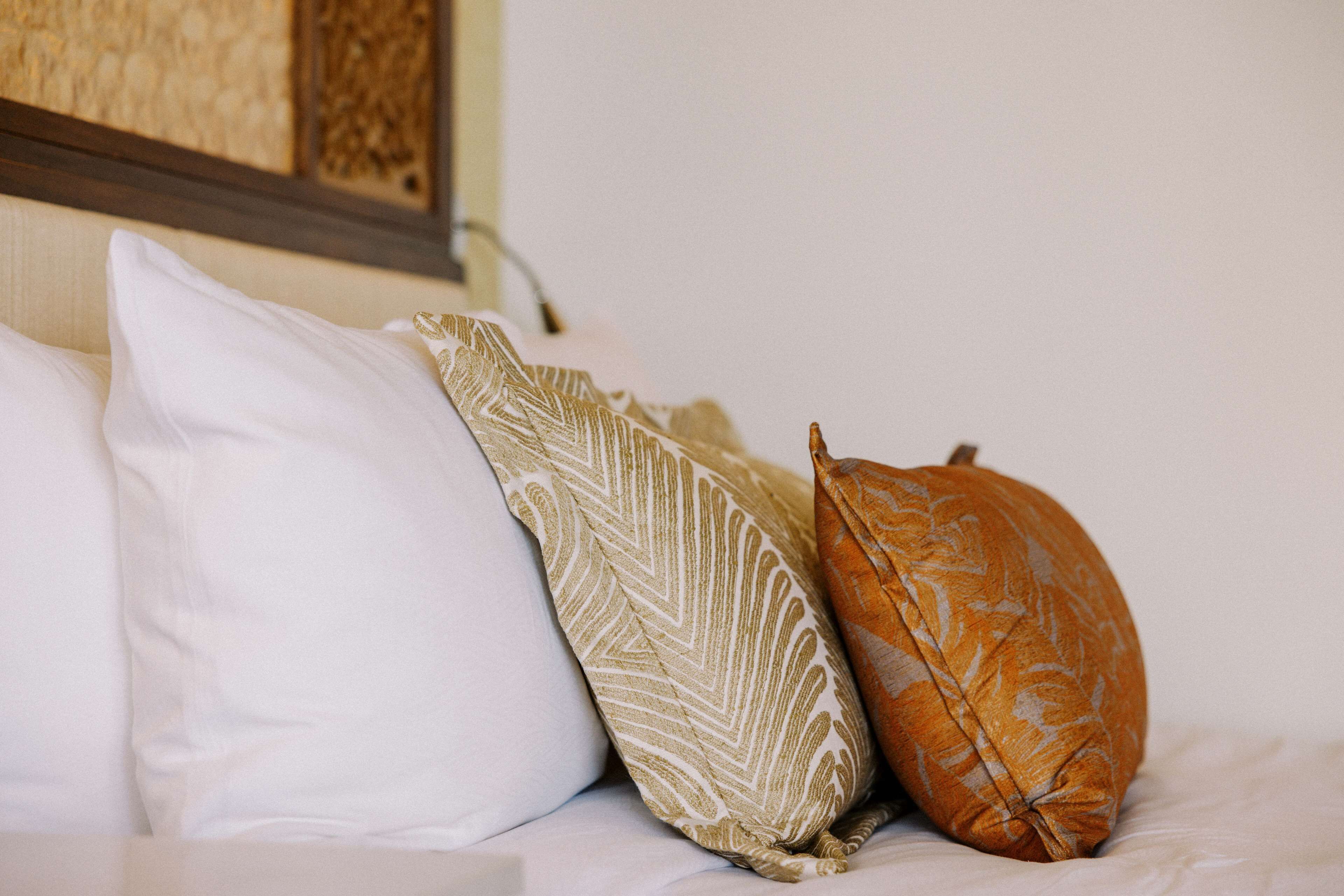 Uma cama com três almofadas de diferentes padrões e cores.